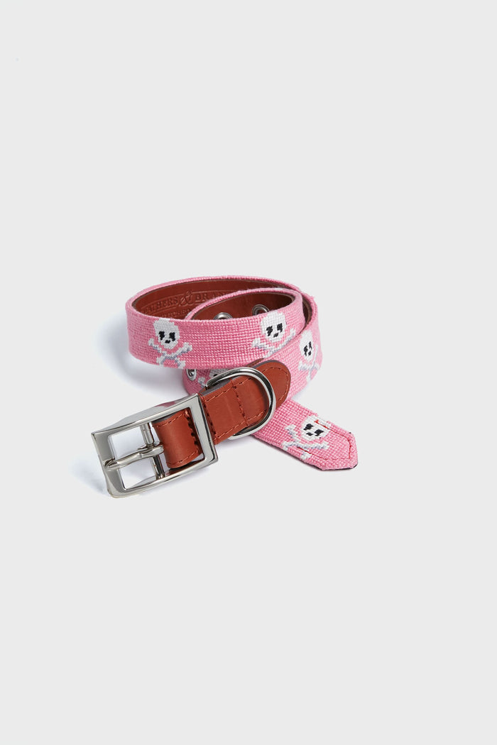 A Smathers and Branson pink needlepoint dog collar features white skull patterns, brown leather accents, and a silver buckle.