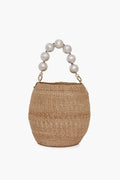 The Clare V handwoven straw bag features a handle with large white beads, making it a chic choice for a beach basket tote.