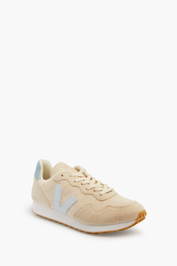 The VEJA conscious sneaker features beige vegan suede, a white sole, light blue heel tab, and a light blue V logo on the side for an eco-friendly look.