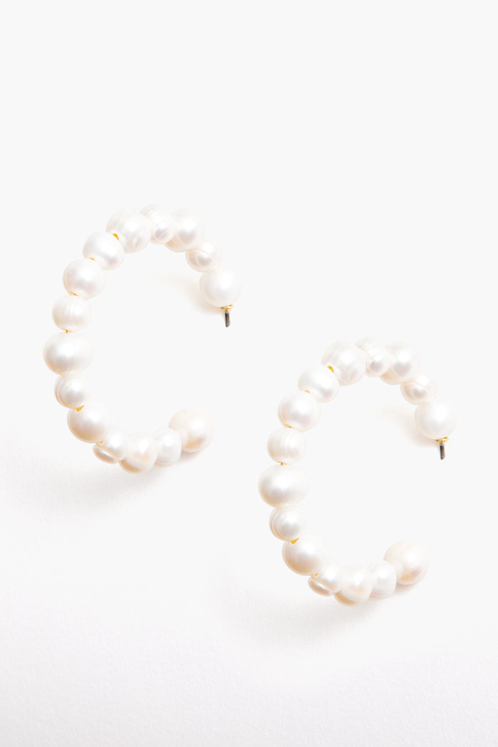 Tuckernuck Jewelry’s pearl hoop earrings feature round freshwater pearls in a semi-circle design. These hypoallergenic earrings provide timeless elegance and comfort for every occasion.
