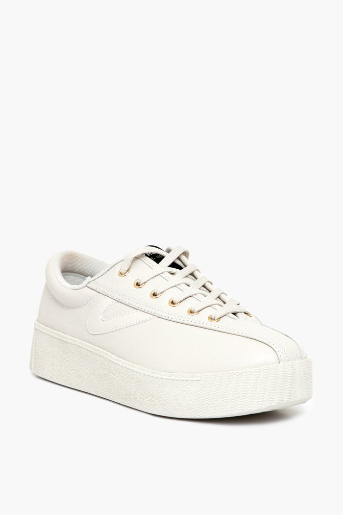 The Tretorn white low-top leather platform sneaker features gold eyelets, a textured platform sole, white laces, and a non-marking rubber outsole that ensures superior traction.