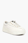 The Tretorn white low-top leather platform sneaker features gold eyelets, a textured platform sole, white laces, and a non-marking rubber outsole that ensures superior traction.
