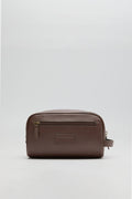 A Barbour leather wash bag in brown featuring a front zip pocket, embossed Barbour logo, and side handle, crafted from durable leather.