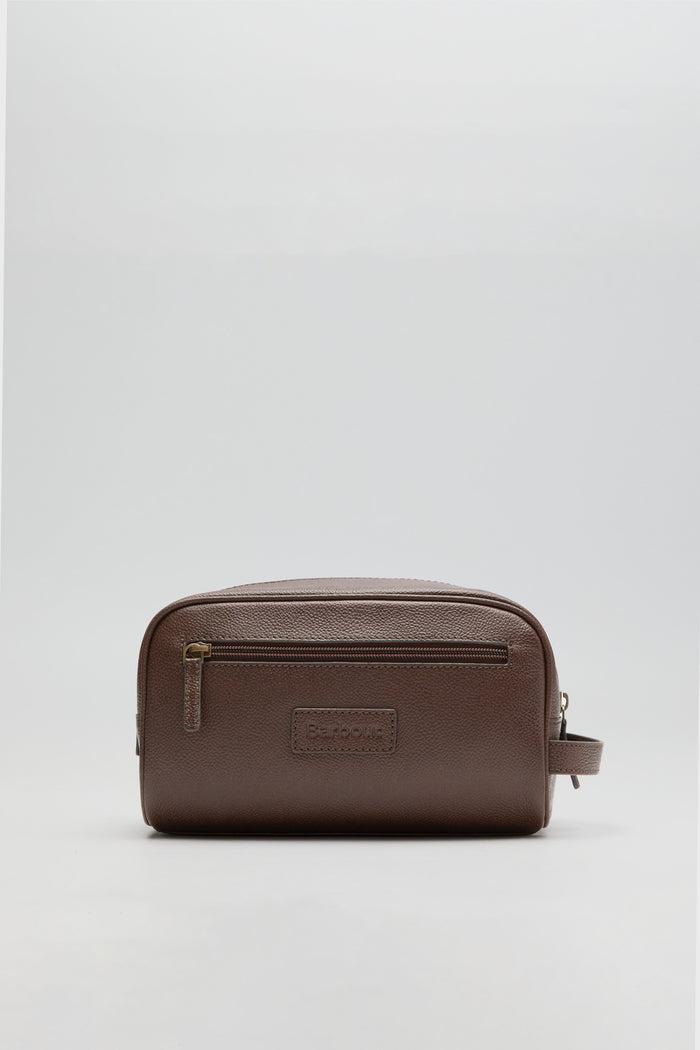 A Barbour leather wash bag in brown featuring a front zip pocket, embossed Barbour logo, and side handle, crafted from durable leather.