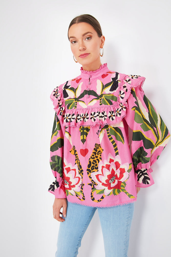 A woman wears a Farm Rio Leopard Forest Pink Blouse with bold floral and animal prints and ruffled details, paired with light blue jeans, adding vibrant flair to her look.