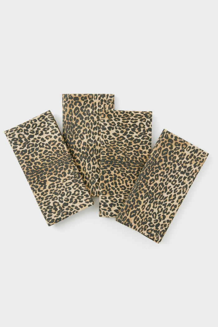 A set of 4 rectangular cotton napkins from Tuckernuck Home features a brown and black leopard print, stylishly arranged in a slightly overlapping display to elevate your table decor.