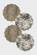 Four scalloped round reversible placemats by Tuckernuck Home: two with leopard print and two with black and white tropical foliage. Made from wipeable polyurethane leather for easy care.