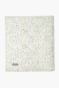 A folded Louelle. white quilt with a colorful floral pattern, small flowers and leaves, plus a gray corner label makes a charming linen play mat—ideal for luxury baby gifts.
