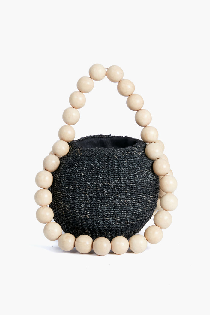 The Aranaz round black woven handbag features a handle made of large, light wooden beads—a striking handmade statement accessory.