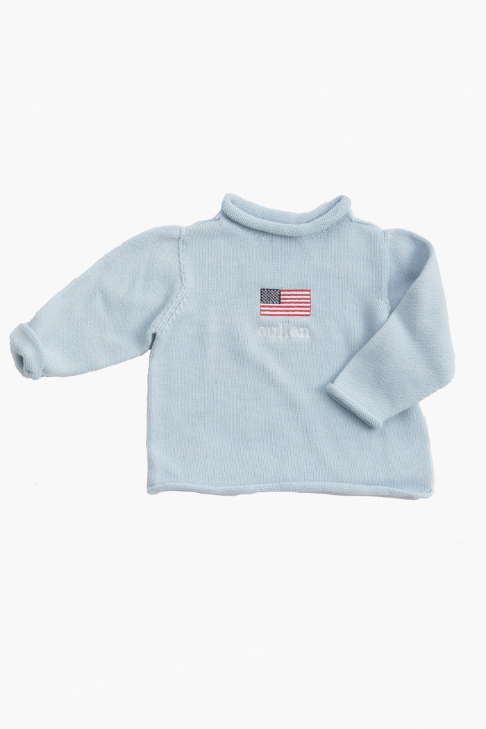 A Soft Idea light blue long-sleeve cotton baby sweater with an embroidered American flag and subtle chest text. Made in the USA and machine washable.