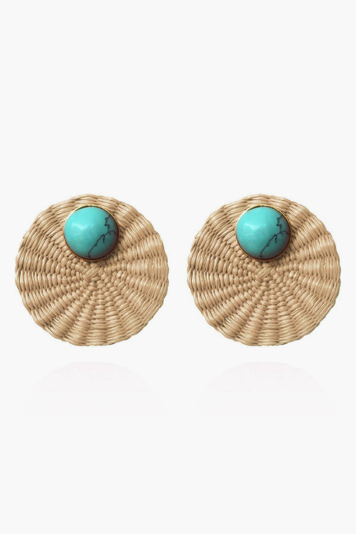 Round, woven straw earrings by Ana Carolina Valencia, handcrafted from iraca palm with a prominent turquoise stone at the top center and light brown studs for a natural, stylish accent.