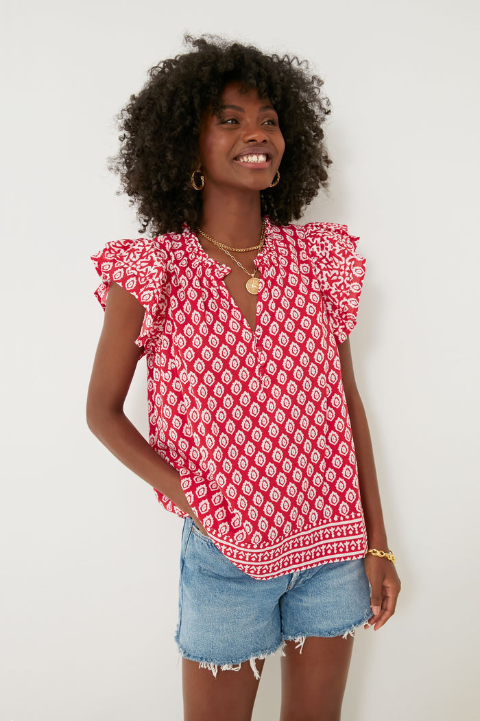 A woman with curly hair smiles, wearing a Vineyard Vines Lighthouse Red Tile Ruffle Top.