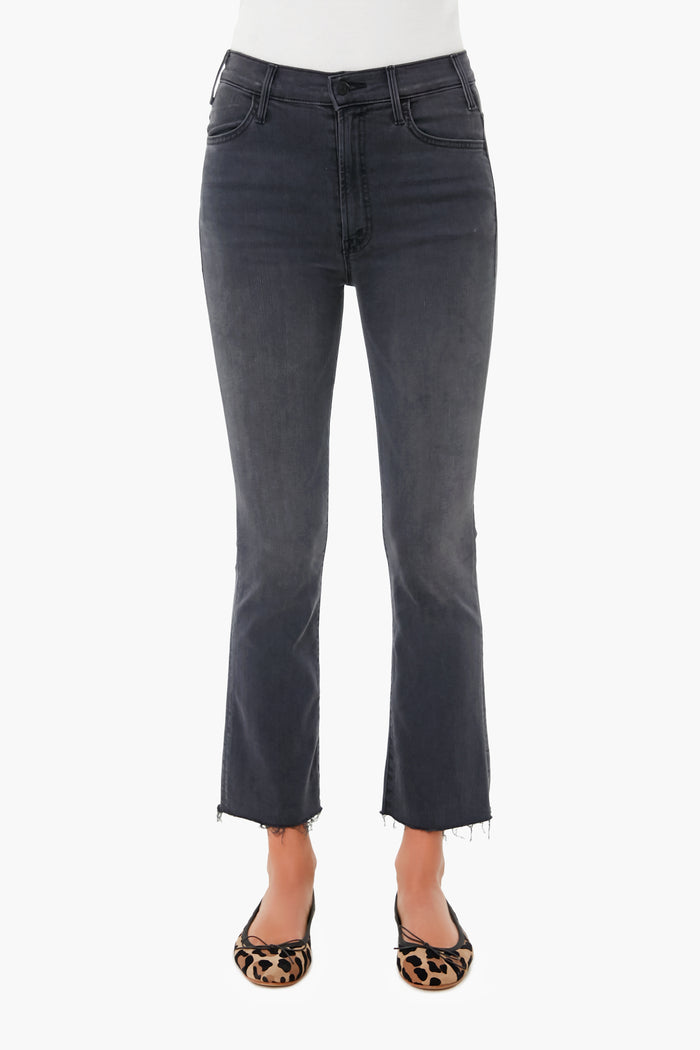 A person is shown from the waist down wearing MOTHER high-waisted, dark gray straight-leg jeans with raw hems and leopard-print flats.
