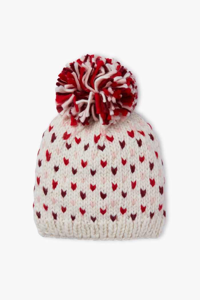 The Look by M white knit hat features red and pink heart patterns and a large red-and-white pompom, making this handmade beanie perfect for cozy style.