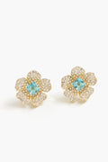 Nicola Bathie gold flower studs feature petals encrusted with small clear stones and a London Blue gemstone at the center, crafted in a 14k gold-plated finish.