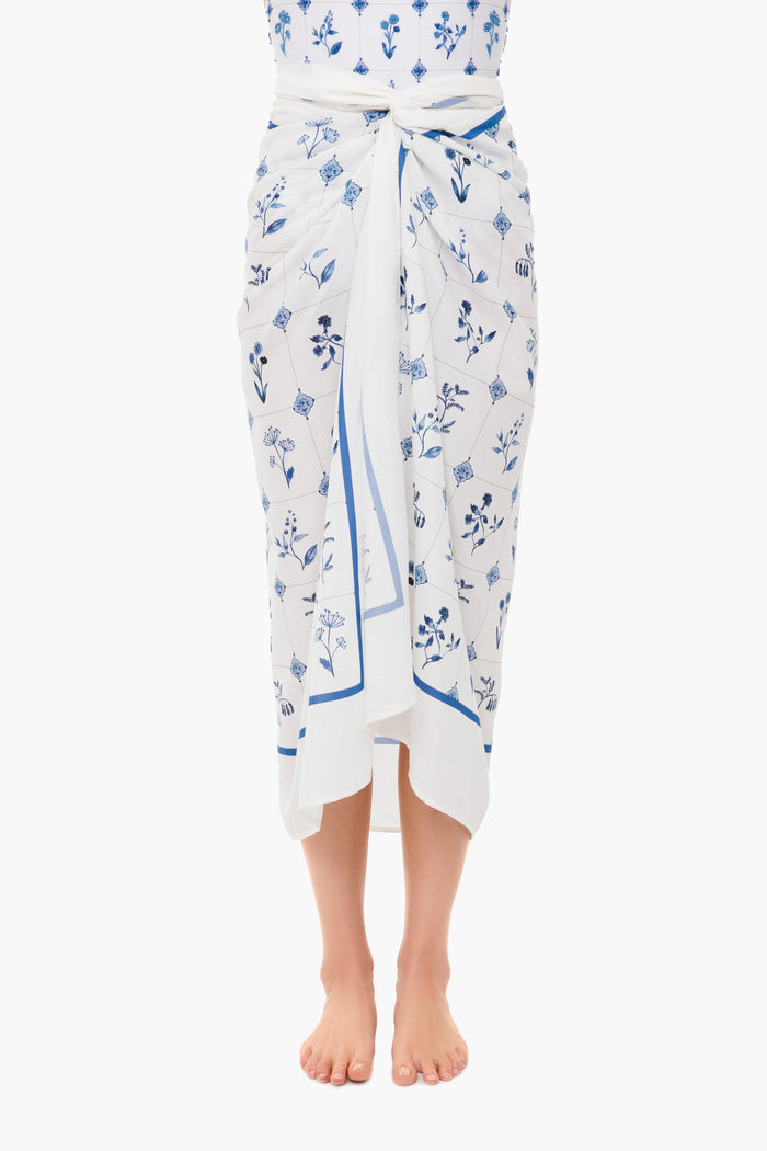 A person stands barefoot, wearing a cotton silk floral pareo by AGUA BY AGUA BENDITA, tied at the waist. The upper body is partially visible.