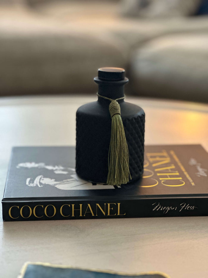 Black 200ml diffuser bottle sitting on a black book.