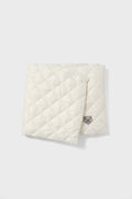 The Powder Puff Collection features a folded, quilted white scarf with a diamond pattern and stitched logo patch, crafted from sustainable materials for a luxurious winter accessory.