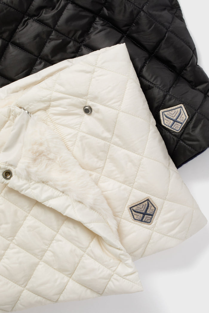 Powder Puff Collection quilted black and white jackets with fur lining, Primaloft® Gold insulation, and geometric logo patches are laid flat, partially overlapping.