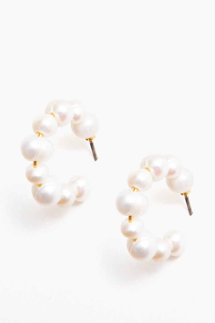 Tuckernuck Jewelry presents hypoallergenic gold hoops with round white pearls in a semi-circle design, secured with metal posts.