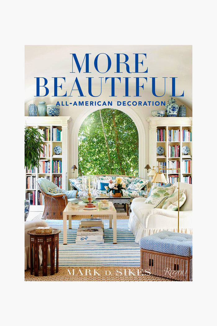Rizzoli's "More Beautiful: All-American Decoration" by Mark D. Sikes features a vibrant cover with floral decor, blue accents, and a grand arched window—an inspiring guide to timeless American interiors.