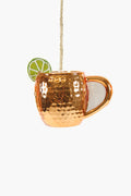 A Cody Foster Moscow Mule glass Christmas ornament shaped like a copper mug, featuring a hammered texture, glitter accents, a lime slice on the rim, and a rope loop for hanging.