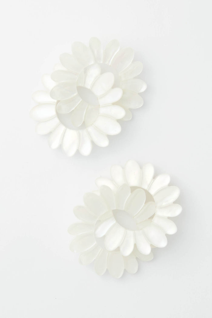 Tuckernuck Jewelry pairs two white, flower-shaped hair clips with petal designs and elegant Mother of Pearl Earrings for a charming accessory ensemble.