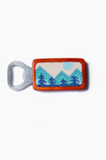 The Smathers and Branson magnetic bottle opener features a rectangular wooden handle with a hand-stitched mountain and sun design in blue and green tones.