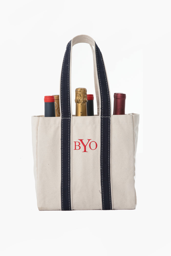 CB Station canvas wine carrier with navy handles and "BYO" embroidered on the front, holds four wine bottles.