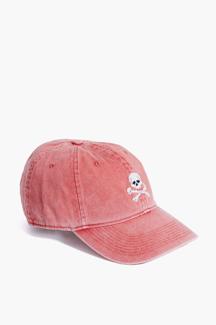 A faded red Smathers and Branson hat featuring a small white hand-stitched needlepoint skull and crossbones Jolly Roger design on the front.