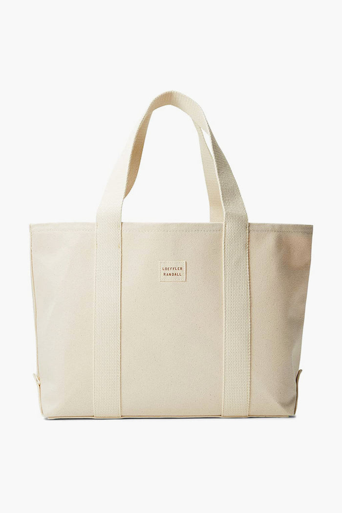 This medium beige canvas tote by Loeffler Randall features two handles and a front rectangular logo patch, offering classic style and everyday versatility.