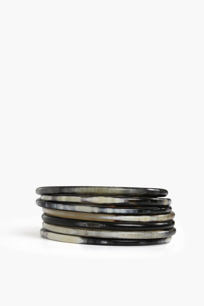 Sunshine Tienda’s set of six thin, round boho bangles features natural horn in marbled shades of black, grey, and beige.