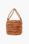 A round, woven wicker basket by Cult Gaia with two handles and a stacked, coiled design, reminiscent of their signature rattan bags.