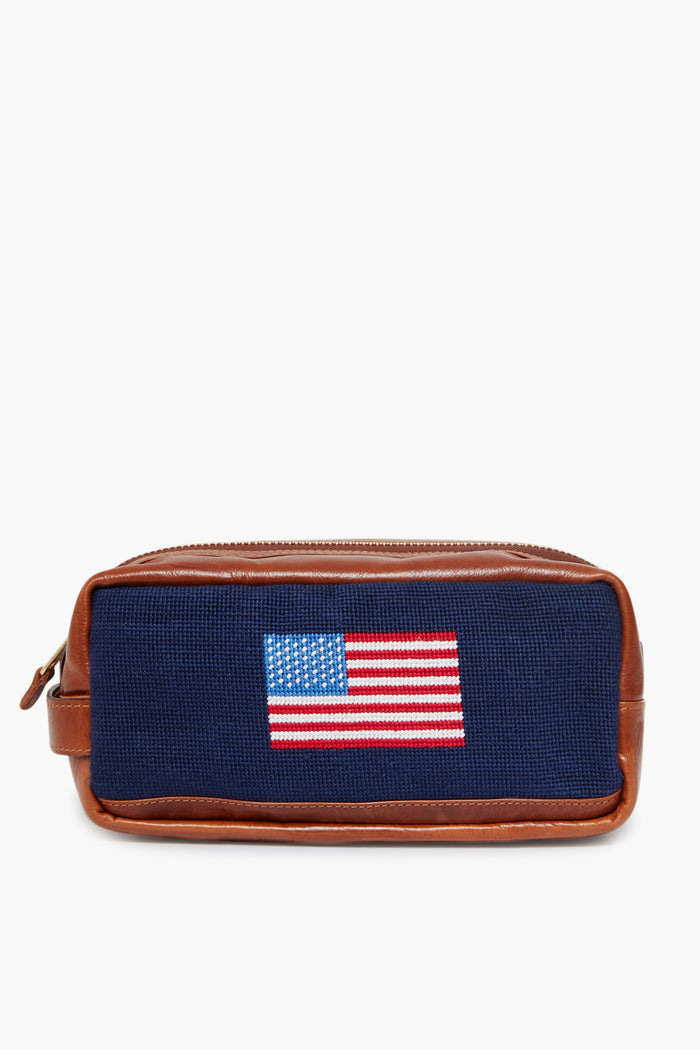 The Smathers and Branson Navy American Flag Needlepoint Toiletry Bag is crafted from Italian leather, with hand-stitched needlepoint and an embroidered American flag on the front.