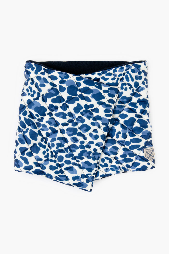 The Powder Puff Collection features a sustainable quilted neck warmer in blue and white with an abstract spotted pattern, designed as a stylish winter accessory.