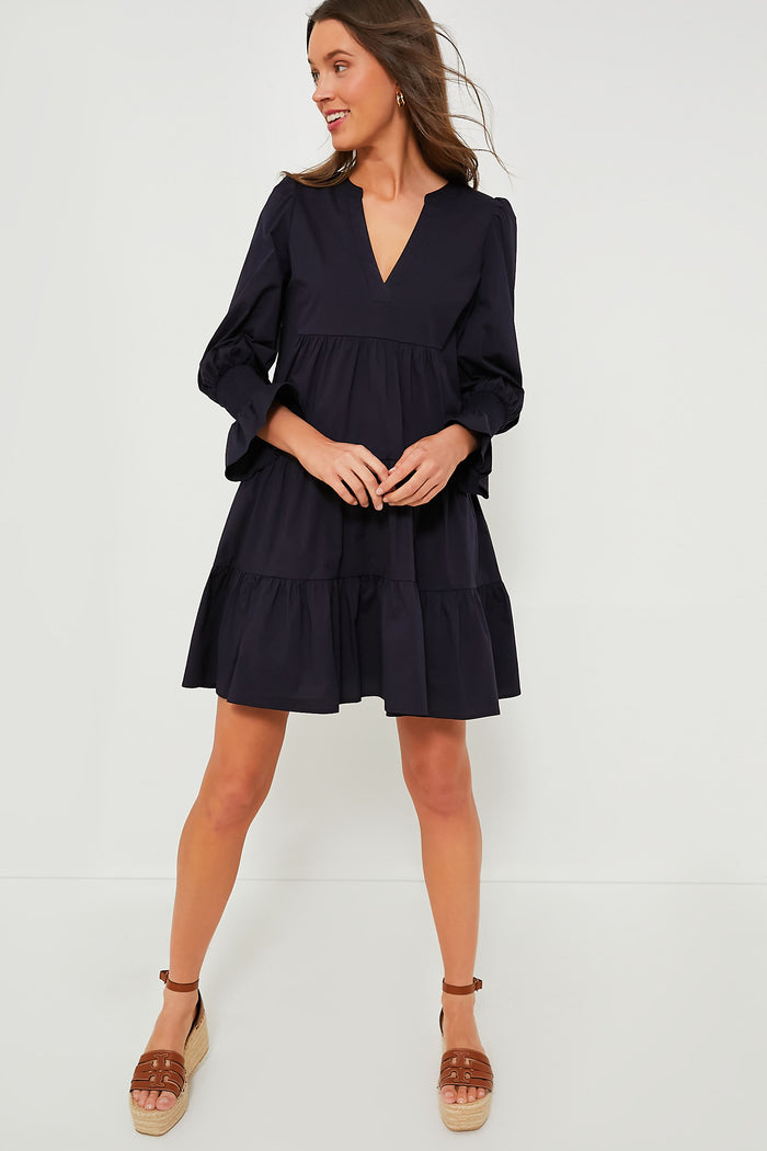 Woman wearing the classic, effortless Navy Cotton Poplin Kenzo Dress; a high-end, loose-fitting V-neck with tiered skirt and flutter smocked wrists, paired with fun tan espadrilles.