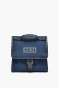 A blue YETI insulated lunch bag with a gray handle and trim, YETI logo on the front, and buckle closure—durable and perfect as an outdoor cooler.