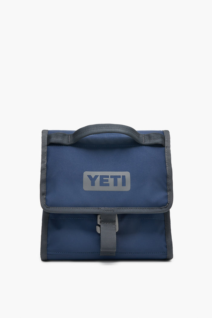 A blue YETI insulated lunch bag with a gray handle and trim, YETI logo on the front, and buckle closure—durable and perfect as an outdoor cooler.