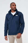 A man wears a Helly Hansen navy waterproof jacket over a white shirt and beige pants.