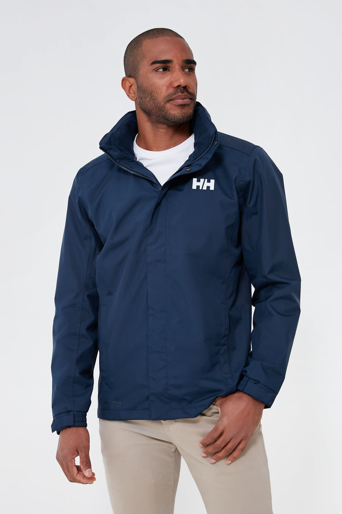 A man wears a Helly Hansen navy waterproof jacket over a white shirt and beige pants.