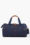The Neely & Chloe navy blue gym duffel bag features dual handles, brown leather accents on the handles and zipper pulls, plus a detachable shoulder strap—an ideal blend of durability, function, and style for everyday use.