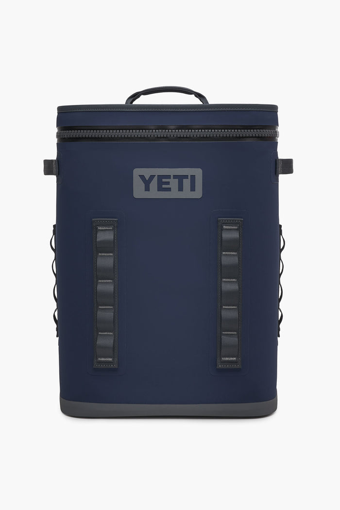 The YETI Hopper BackFlip is a navy blue backpack cooler featuring a top handle, front zipper, side loops, and the YETI logo. Designed by YETI for portability and durability, this leakproof cooler is perfect for on-the-go use.