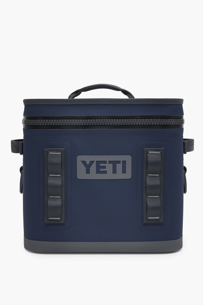 A YETI navy blue Hopper Flip soft cooler featuring a zipper top, carrying handle, and two side straps—ideal for outdoor adventures.
