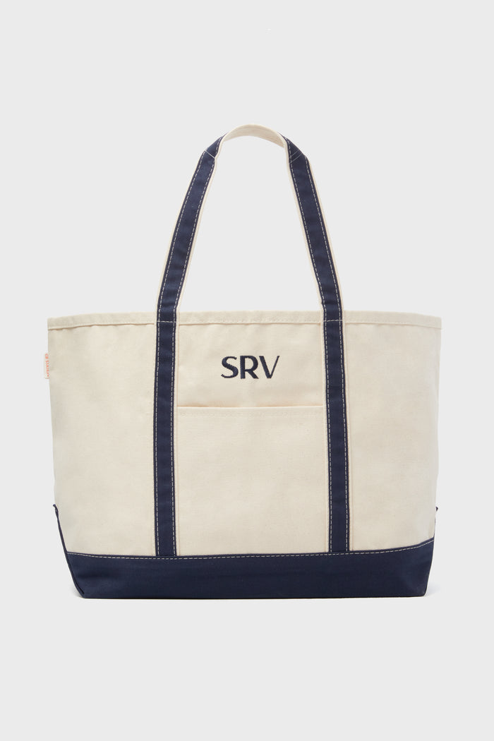 The CB Station beige canvas tote bag features navy blue handles, trim, and a custom SRV monogram embroidered on the front—ideal as a reusable everyday bag.