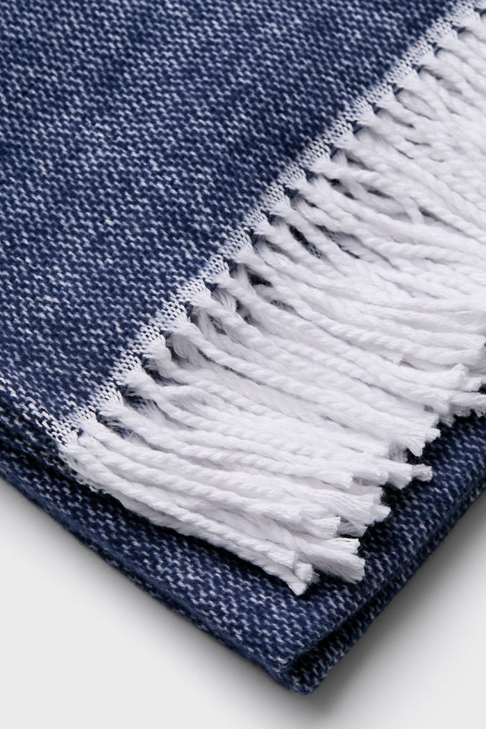 Navy Pezzo Throw with a classic blue-and-white heathered weave and fun white fringe, embodying effortless style and high-end craftsmanship.