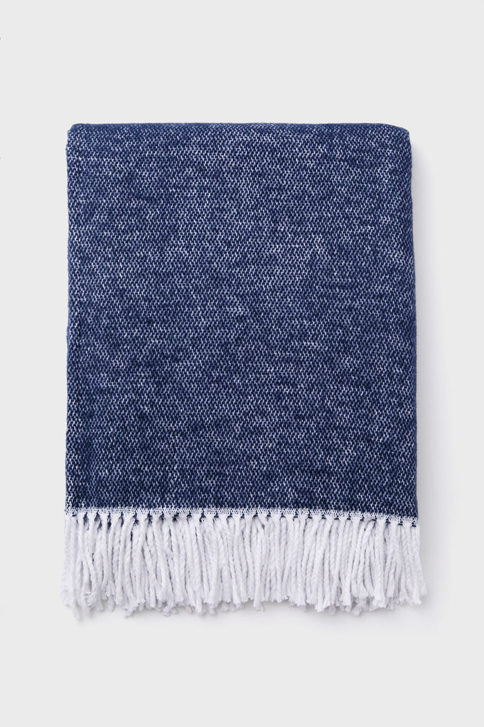 Classic Navy Pezzo Throw with white fringe tassels, blending effortless style and high-end craftsmanship, perfect for adding fun elegance to any lounging space.