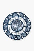The Coro Cora round handmade placemat, in navy blue with a geometric and scalloped edge design, is crafted from natural fibers to add artisan style to your table.