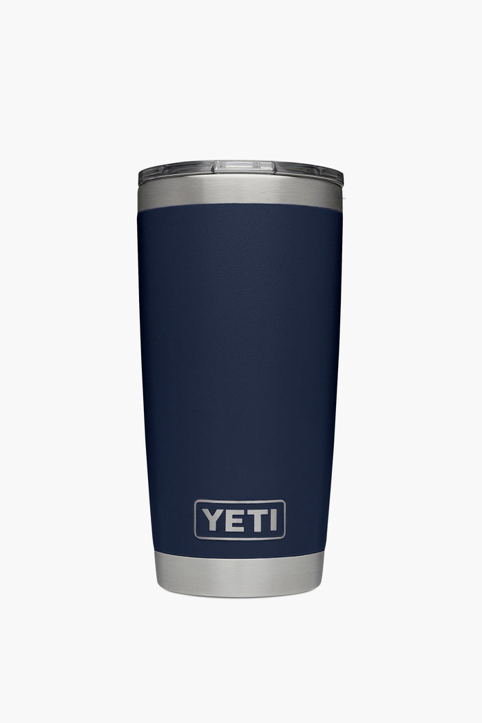 A YETI Rambler navy blue stainless steel tumbler with a silver base and lid is shown, featuring double-wall vacuum insulation.
