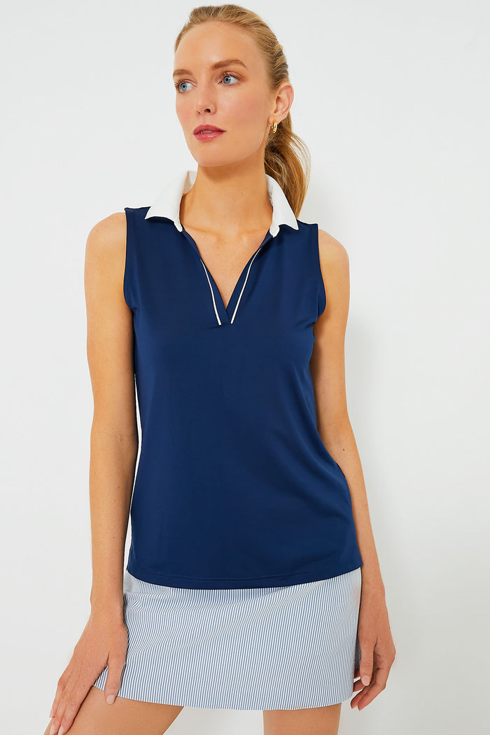 A woman wears a Tnuck Sport sleeveless navy Caroline Polo with a white collar and a light blue and white striped skirt, both made from UPF 30, sweat-wicking performance fabric.