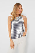 A woman smiles with one hand in her pocket, wearing a Pomander Place Navy Stripe Anthos Shell sleeveless tank and white pants.